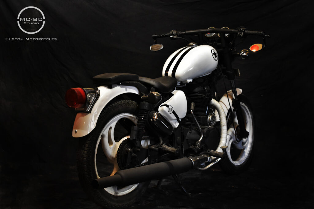 MCBC Studio custom modified motorcycle royal enfield bullet Thunderbird with an all-white paintjob with black streaks along with custom seats, custom painted mag wheels and accessories